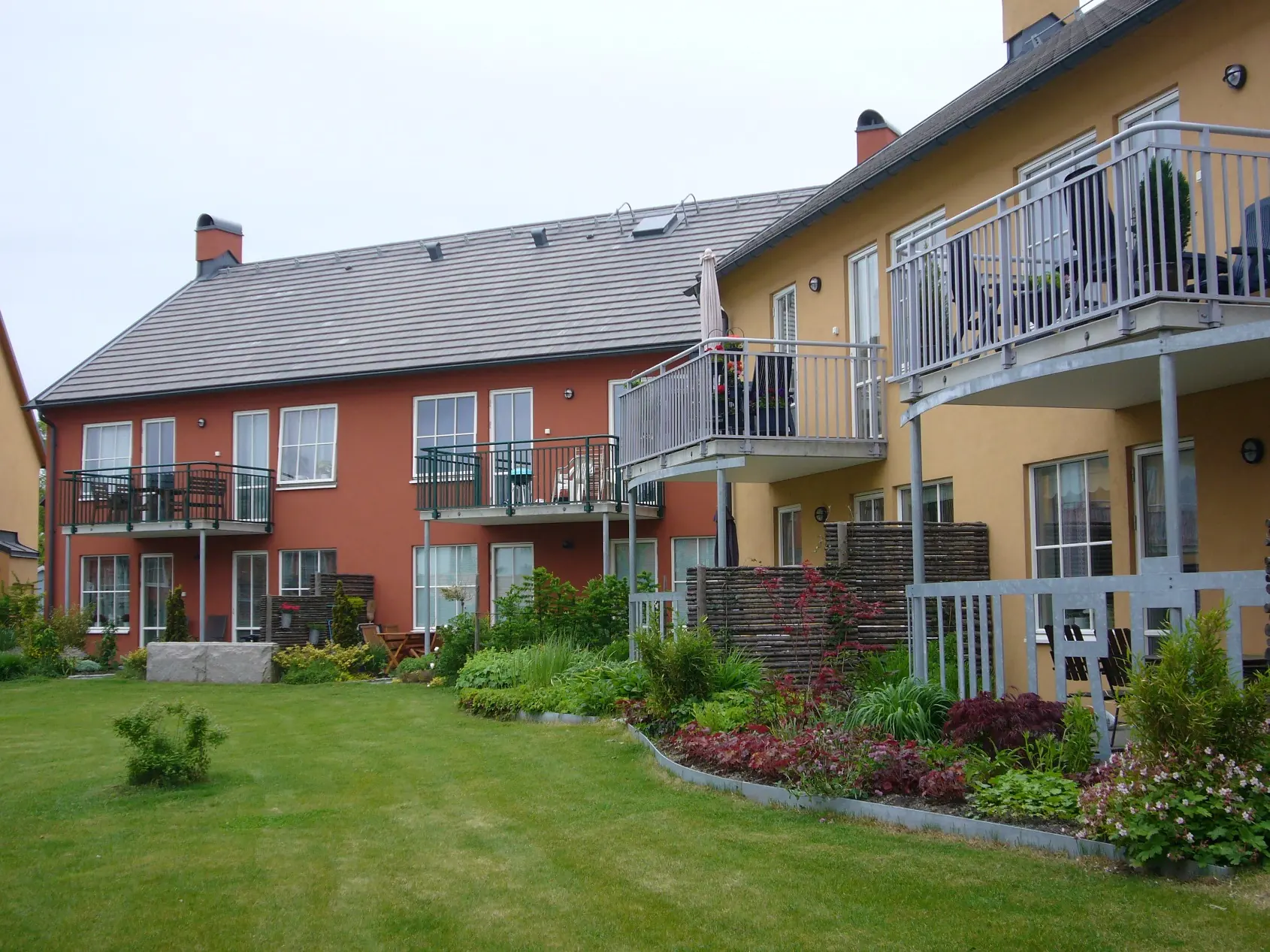 Gul- och terrakottafärgade bostadshus runt en grön gård