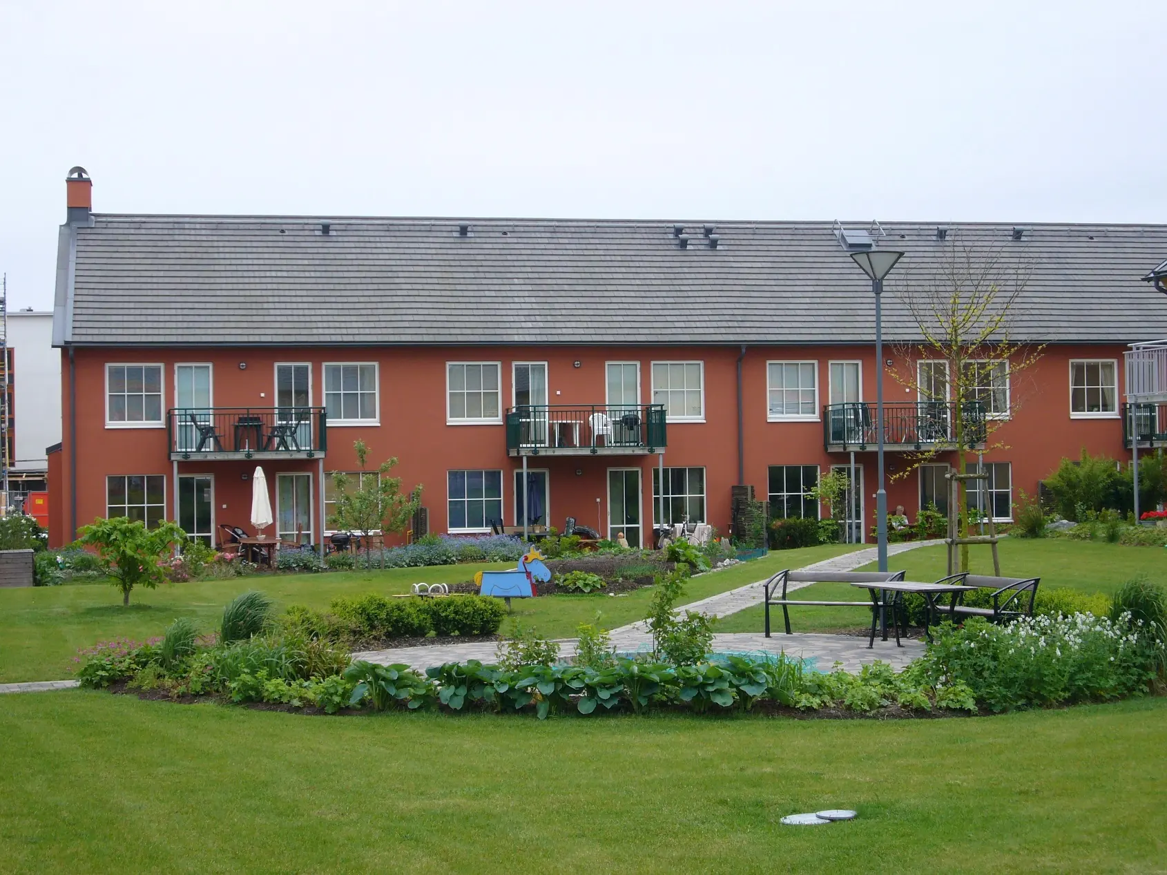 En gemensam gård med planteringar, sittplatser och röda bostadshus